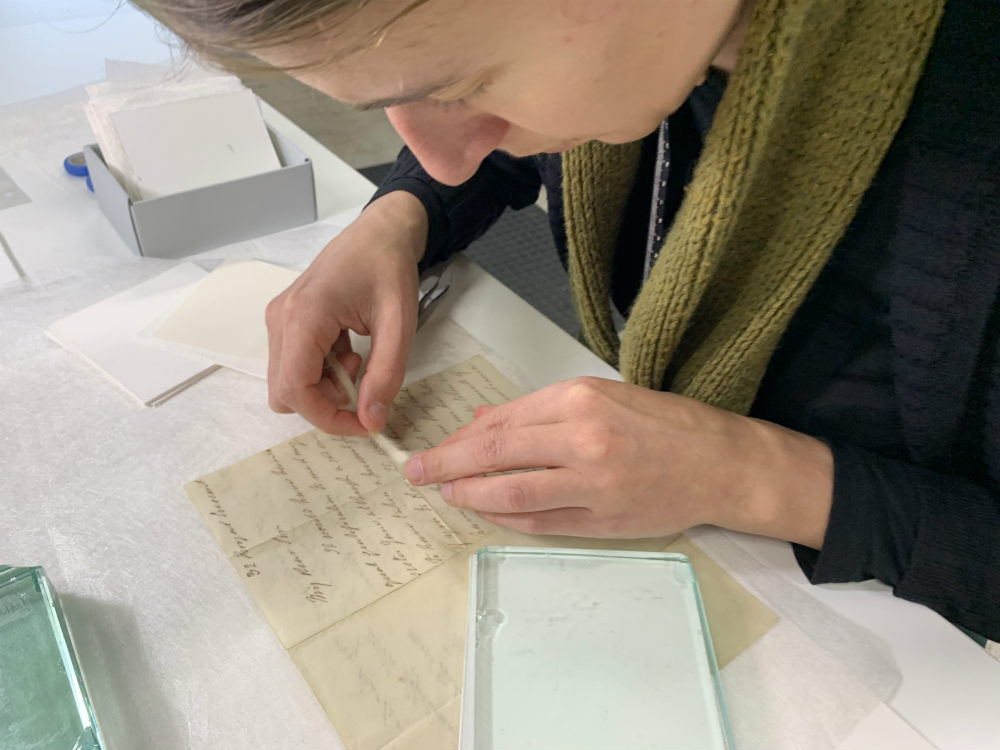 Conservator Katie working out the appropriate size to cut the Japanese tissue paper repairs 