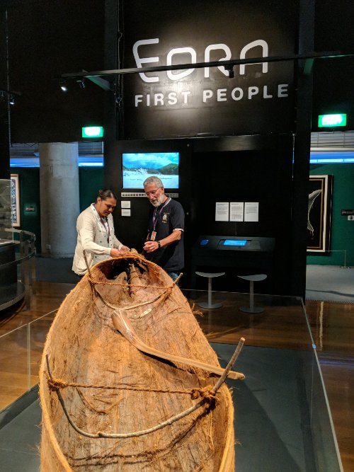 Two people standing next to Indigenous canoe