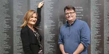 Left to right: Settlement Services International CEO, Violet Roumeliotis and Australian National Maritime Museum CEO, Kevin Sumption standing in front of the Welcome Wall