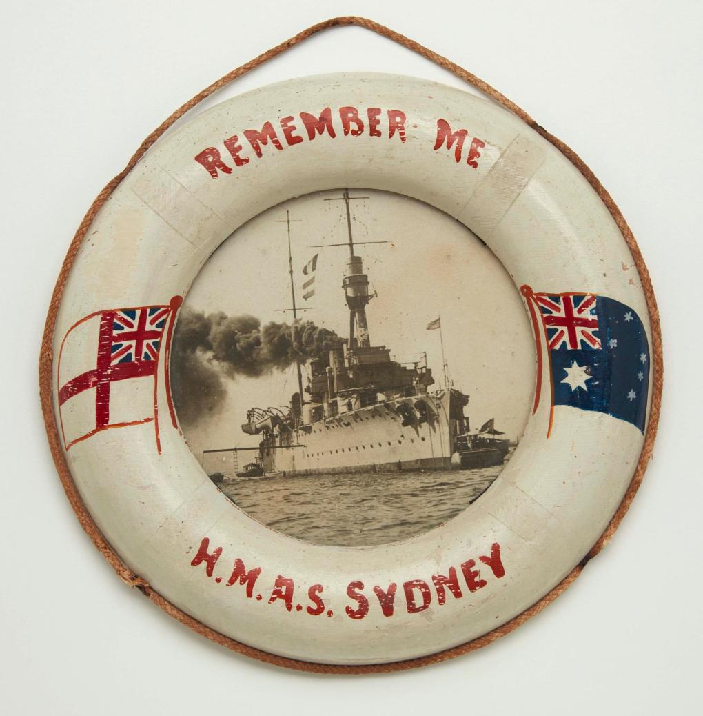Miniature commemorative wooden lifebuoy reading 'Remember Me - HMAS SYDNEY', mounting a photograph of HMAS SYDNEY. ANMM Collection 00018383.