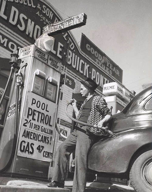 William Russell putting the four-gallon (18-litre) monthly ration of petrol into a customer's car, Drouin, Victoria. Photo by Jim Fitzpatrick [National Library of Australia]