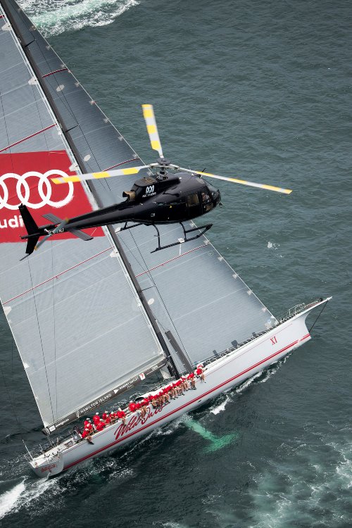 Photograph showing a yacht in the ocean with a helicopter flying past in the air