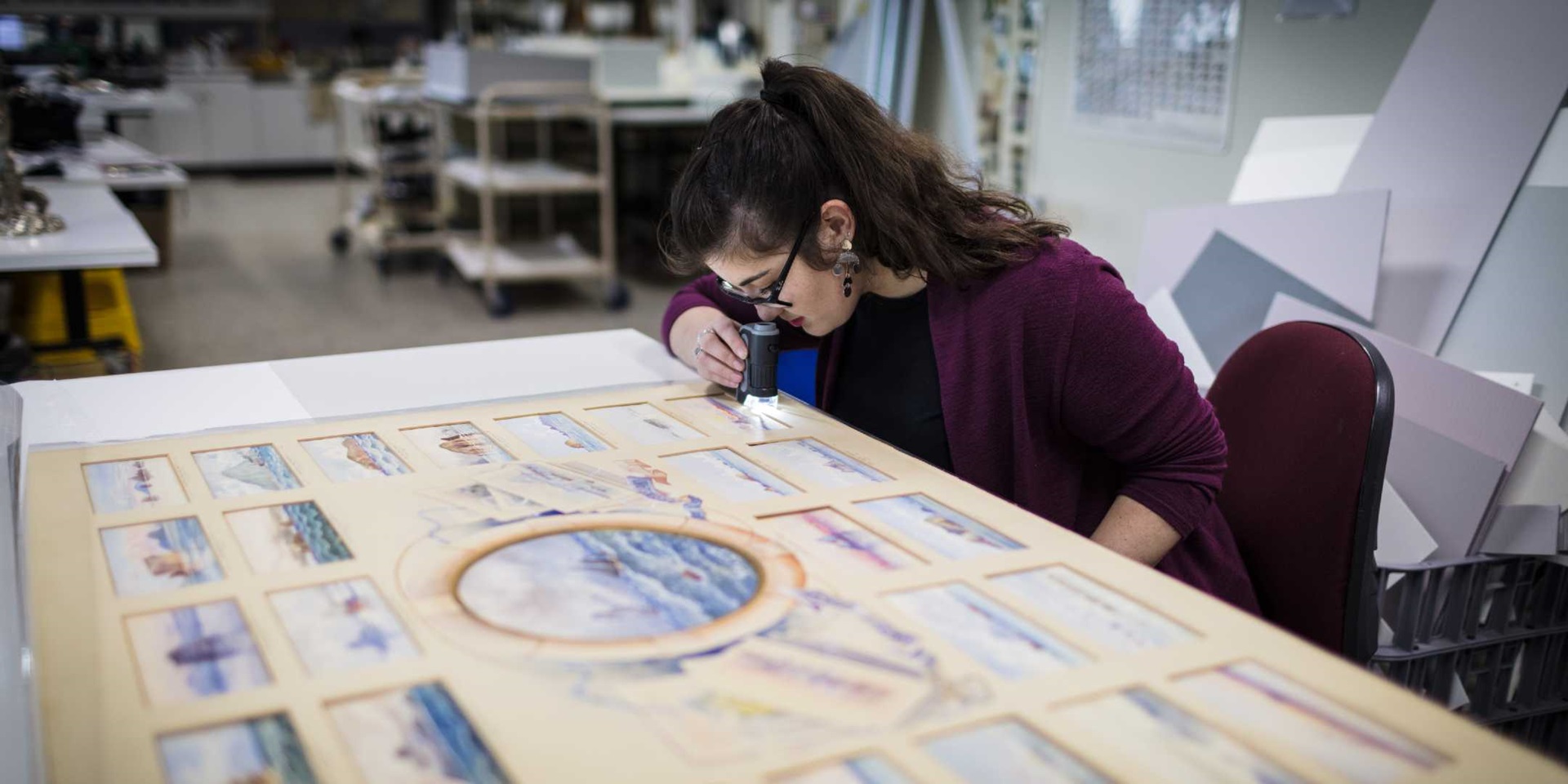 Lucilla Ronai examining the large Frederick Elliot work comprising of many small watercolours. ANMM Collection 00054300