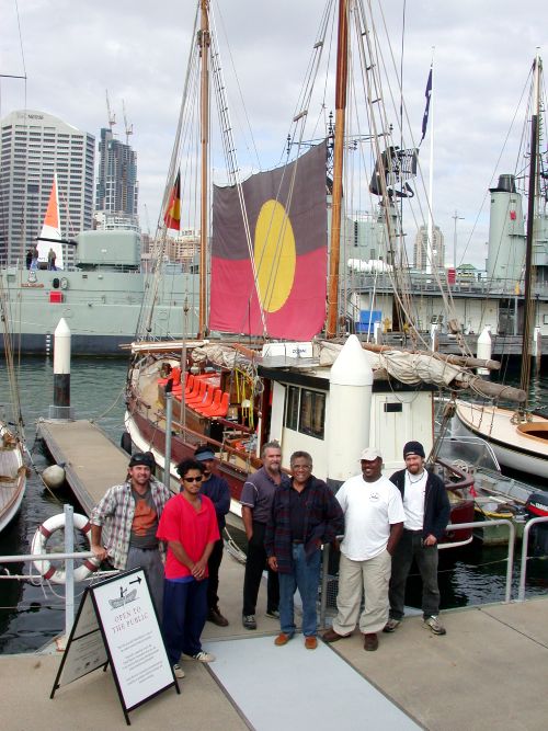 Crew of 'Tribal Warrior' beside the vessel at its mooring at the museum