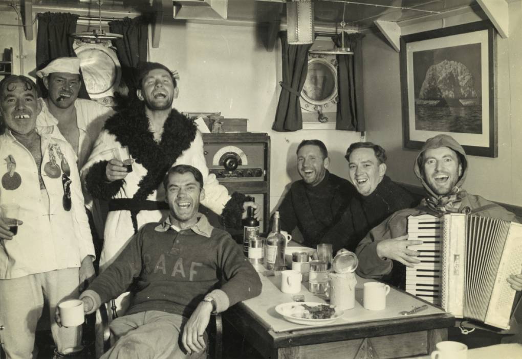 Wyatt Earp officers and ANARE scientists celebrate during an ‘Across the Circle’ party, February 1948. Left to right: LCDR Harold Irwin (Engineer Officer), Dr Tony Bond (Medical Officer), LCDR William Cook, RAAF Squadron Leader Robin Gray (Pilot), ASCB John Homewood (Boatswain), LT John Yule (Watch Keeper), and Phillip Law (Chief Scientific Officer). Australian National Maritime Museum Collection (ANMS1445[127]).
