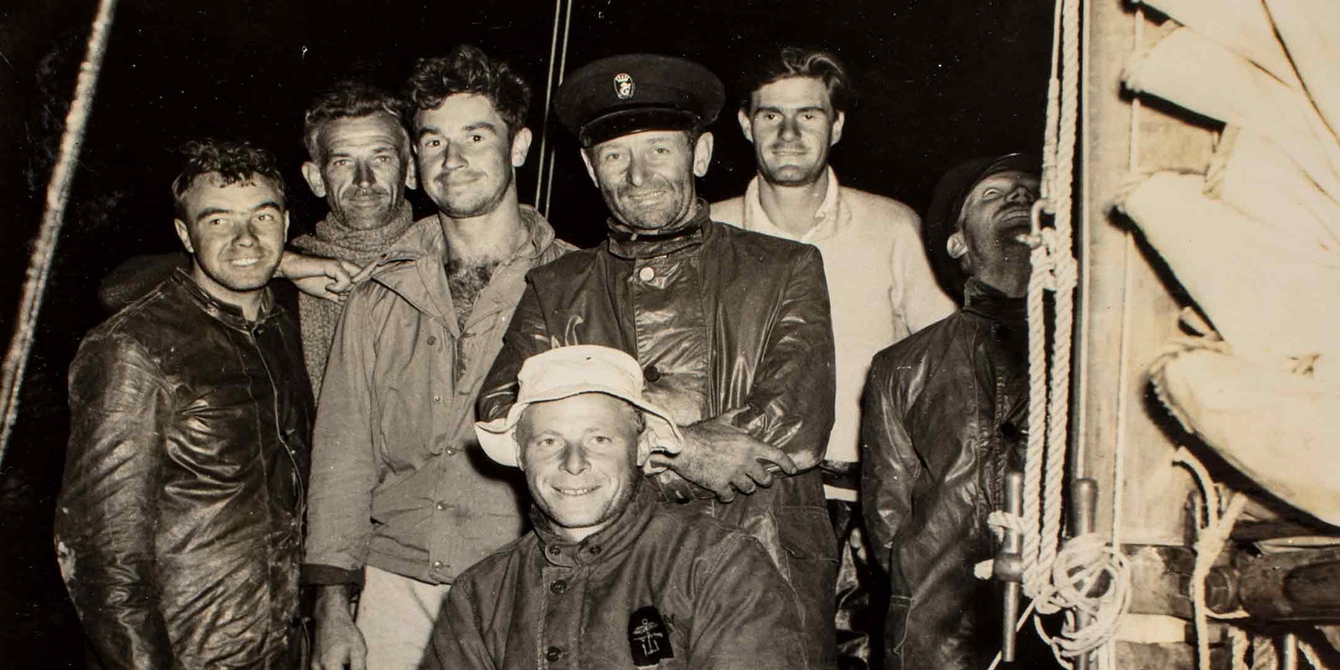 Skipper Captain John Illingworth (centre standing in cap) with the crew of Rani, the winner of the first Sydney to Hobart Yacht Race, 1.45am, 2 January 1946. ANMM Collection 00048228_003, Gift from Alison Richmond