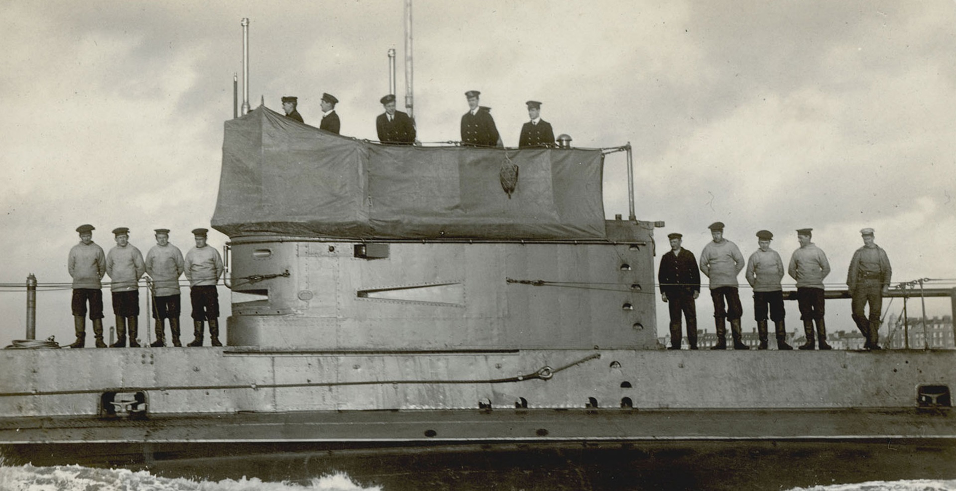 Black and white image of numerous sailors and officers posing on board the submarine HMAS AE2